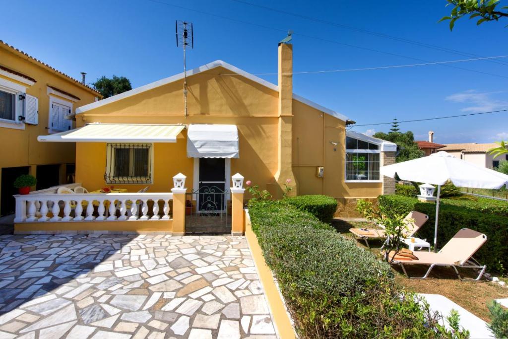 a yellow house with a porch and a patio at Achilleion Holiday Home in Achílleion