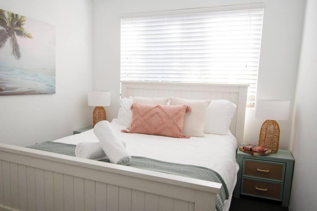 a bedroom with a large white bed with pink pillows at Callie Beach Escape - Beachside View, Family Friendly, Walk Everywhere in Caloundra