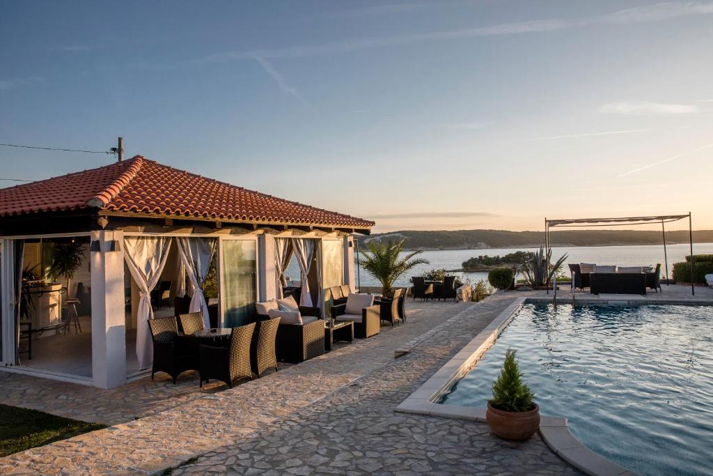 une villa avec une piscine et des chaises au bord de l'eau dans l'établissement Miral Apartments, à Supetarska Draga