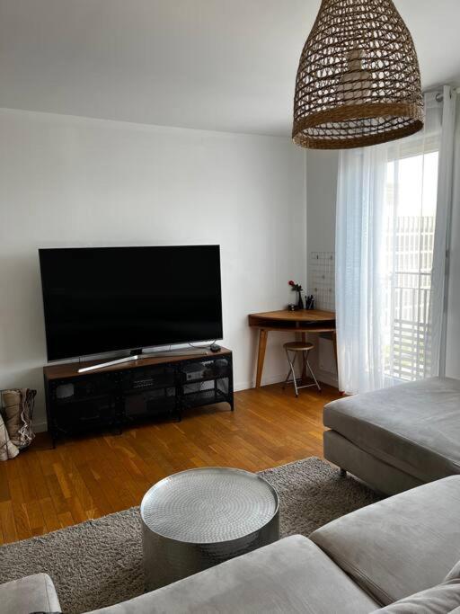 uma sala de estar com uma televisão de ecrã plano e um sofá em Grand T2 La Plaine Saint Denis em Saint-Denis