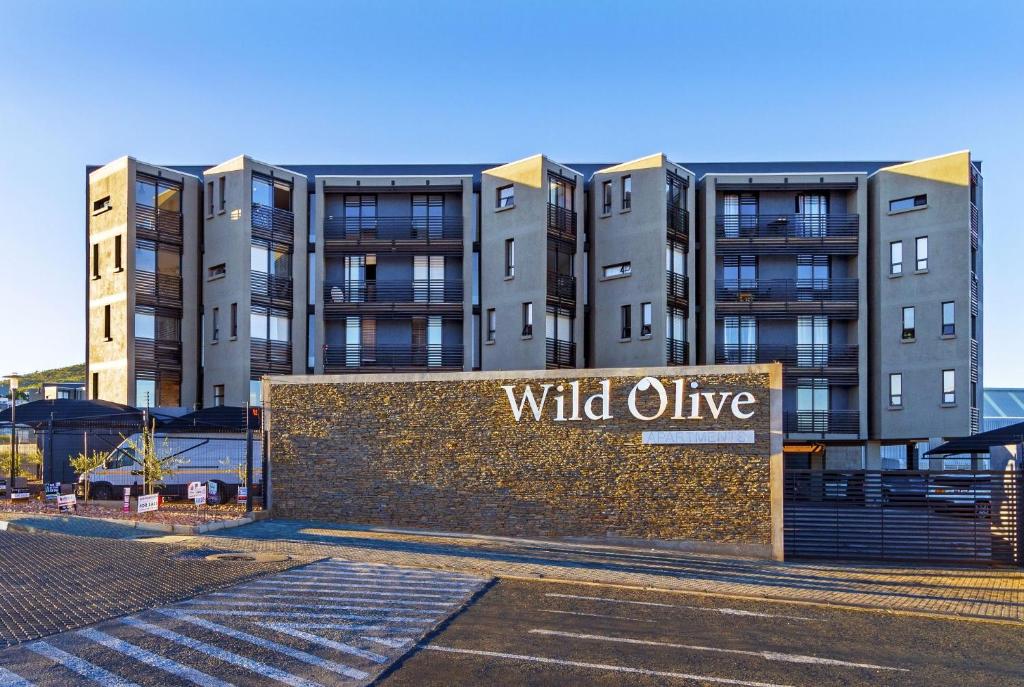 un bâtiment avec un signe d'olive sauvage devant lui dans l'établissement Urban Retreat with a View, à Windhoek