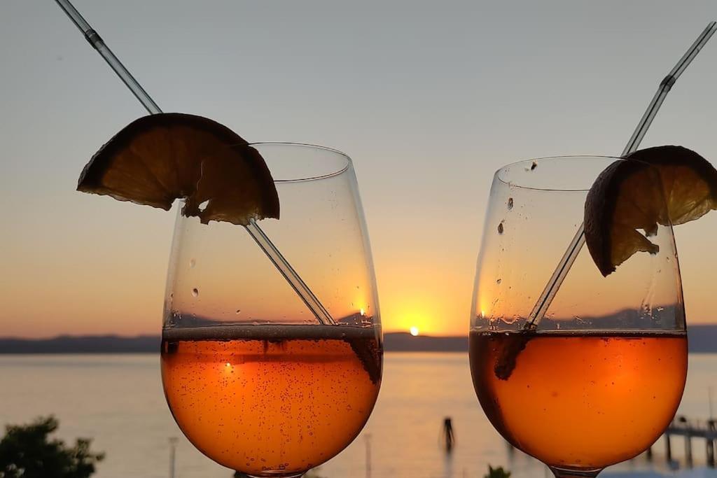 dos copas de vino con una puesta de sol en el fondo en IRIDE sul lago 2 Via Principessa Jolanda 10-Piazza del Molo en Anguillara Sabazia