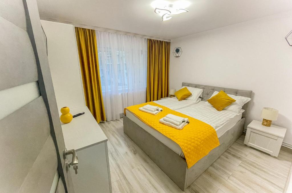 sypialnia z łóżkiem z żółtą pościelą i żółtymi poduszkami w obiekcie Loghin Residence w Suczawie