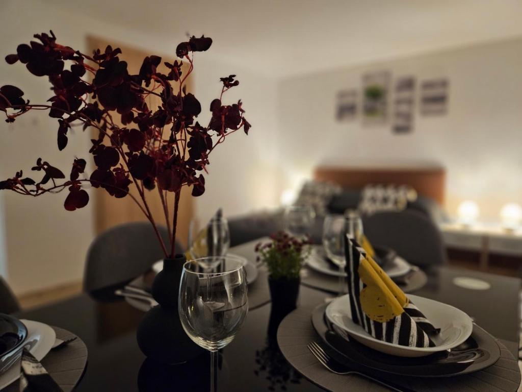 a table with plates and glasses and a vase with flowers at Holiness Apartmanok in Szeged