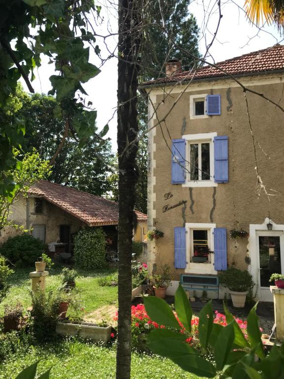 uma casa velha com persianas azuis e flores em La RENAUDIERE em Nassiet