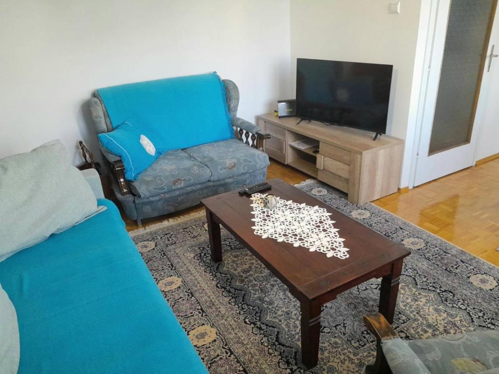 Una sala de estar con un sofá azul y una mesa de café. en Blue Danube Free publlic parking, en Novi Sad