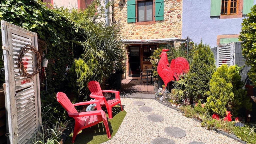 a group of red chairs sitting in a garden at GITE LE COQ ROUGE in Eguisheim