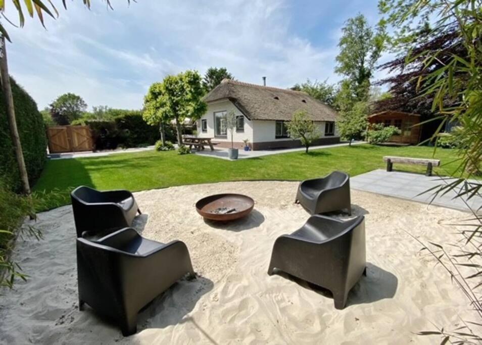 a backyard with two chairs and a table and a house at Luxe villa met geweldige omheinde tuin aan Veluwse bosrand in Ermelo