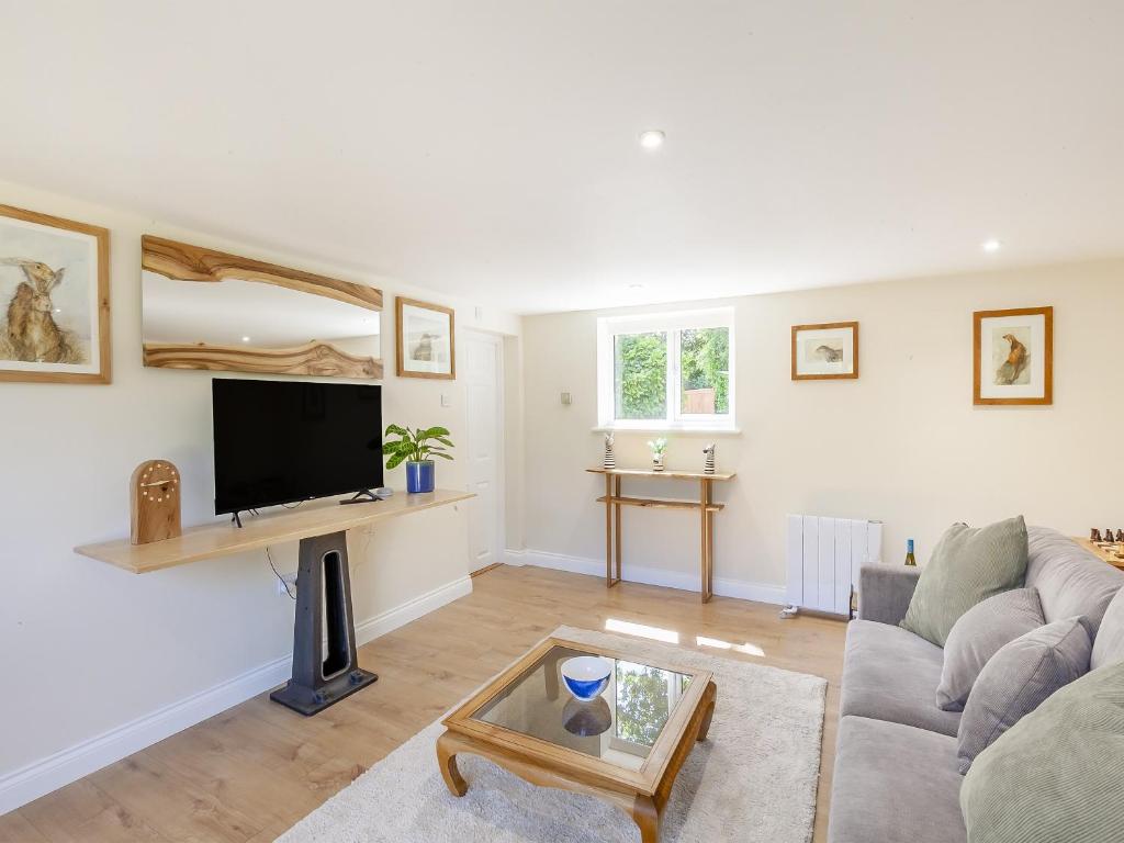 een woonkamer met een bank en een tv bij South Wood Lodge in Slindon