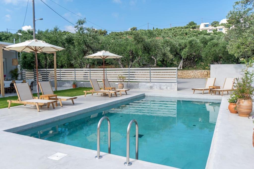 una piscina con sedie e ombrelloni accanto di Villa Estia ad Alikanás