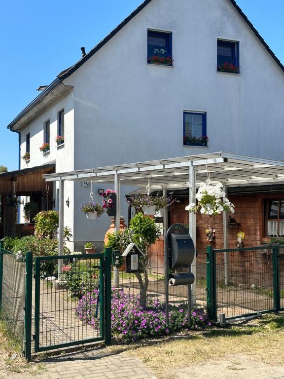 ein Haus mit einem Zaun und Blumen davor in der Unterkunft Ferienwohnung Steffi Lauschke in Gerstenberg