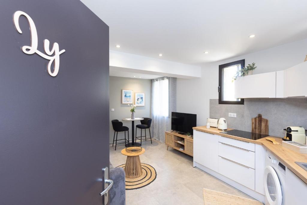 a kitchen with white cabinets and a table with chairs at T2 bord de mer avec garage in Collioure