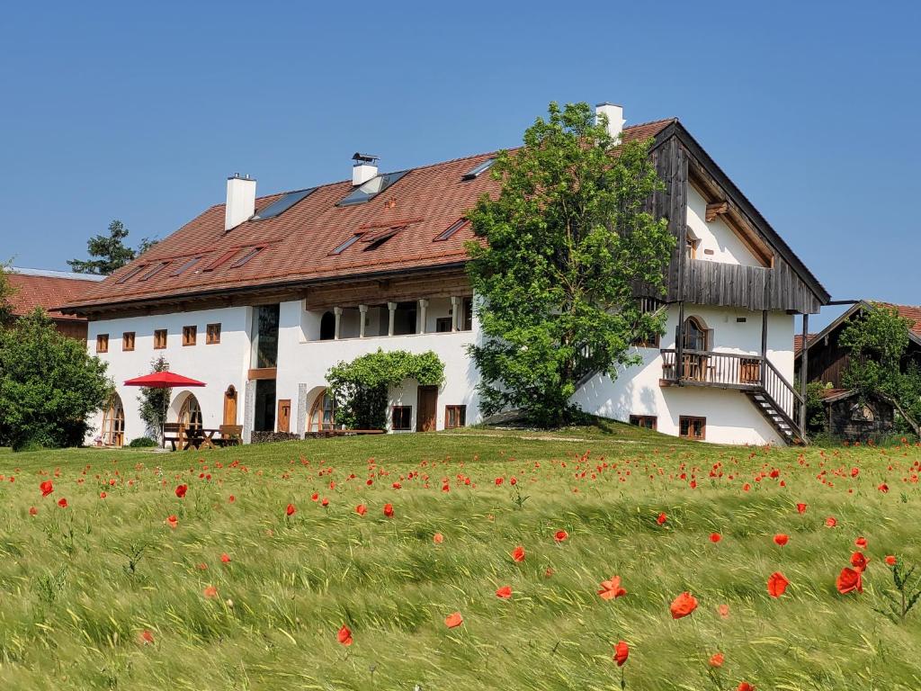 ein Haus mit einem Feld voller roter Blumen davor in der Unterkunft Hagerhof in Eggstätt