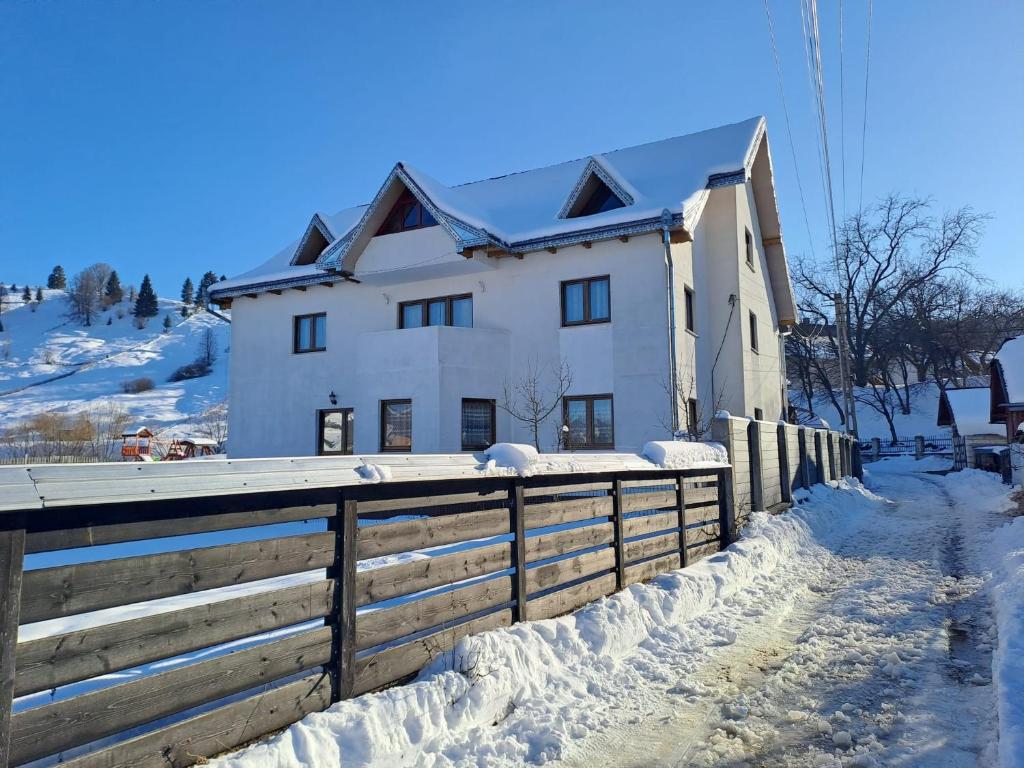 una casa blanca con una cerca en la nieve en Moldovița Residence, en Moldoviţa