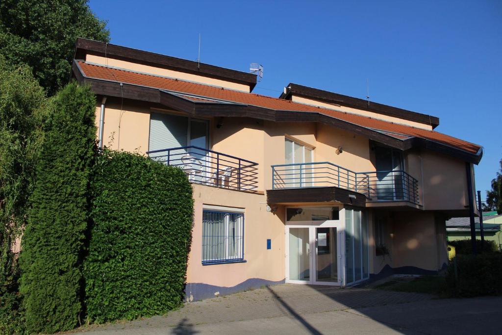 une maison avec une haie verte à côté d'un bâtiment dans l'établissement Chata TARGET Senec, à Senec