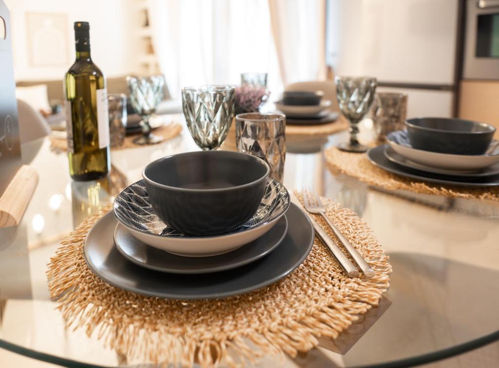 Nefeli Residence في أليكساندروبولي: طاولة زجاجية مع أطباق وزجاجة من النبيذ