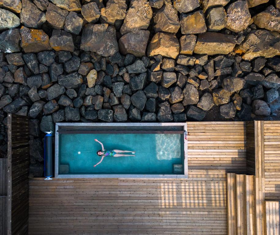 a person swimming in a pool next to a rock wall at Blabjorg Resort in Borgarfjordur Eystri