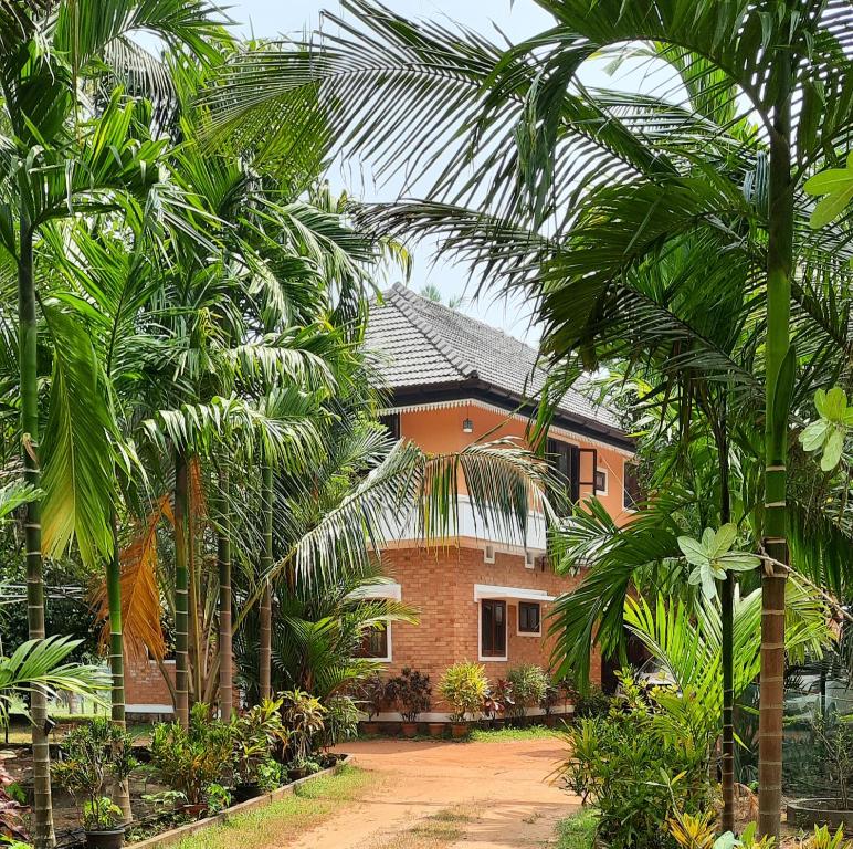 a brick house with palm trees in front of it at Joan's Homestay Near Kumarakom, Aleppey, Marari in Vaikom