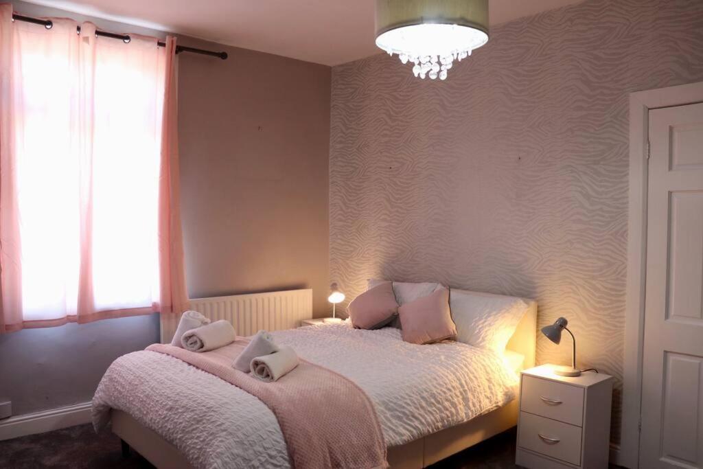 a bedroom with a bed and a window and a chandelier at Elegant Guest House FREE WiFi & Parking in Killingbeck