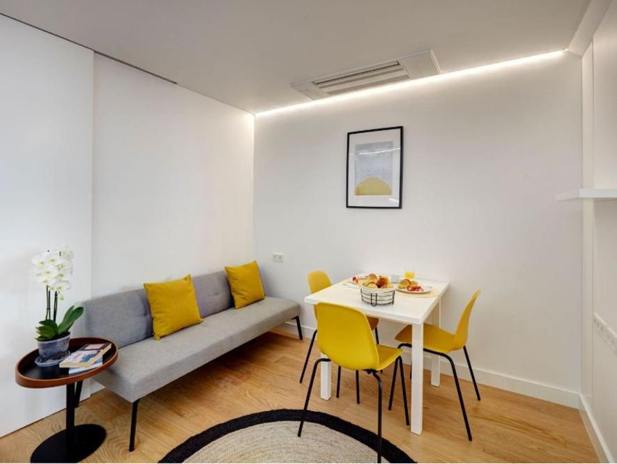 ein Wohnzimmer mit einem Sofa, einem Tisch und gelben Stühlen in der Unterkunft Your Perfect Pantheon Stay in Lissabon