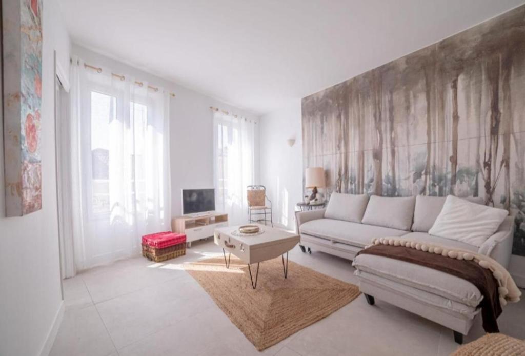 a white living room with a couch and a tv at L'ESCAPADE in Cannes