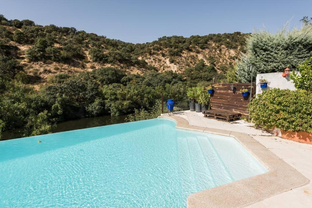 a large blue swimming pool next to a mountain at Casa con vistas increíbles, piscina Infinity y jardín con rincones preciosos in Las Rozas de Madrid