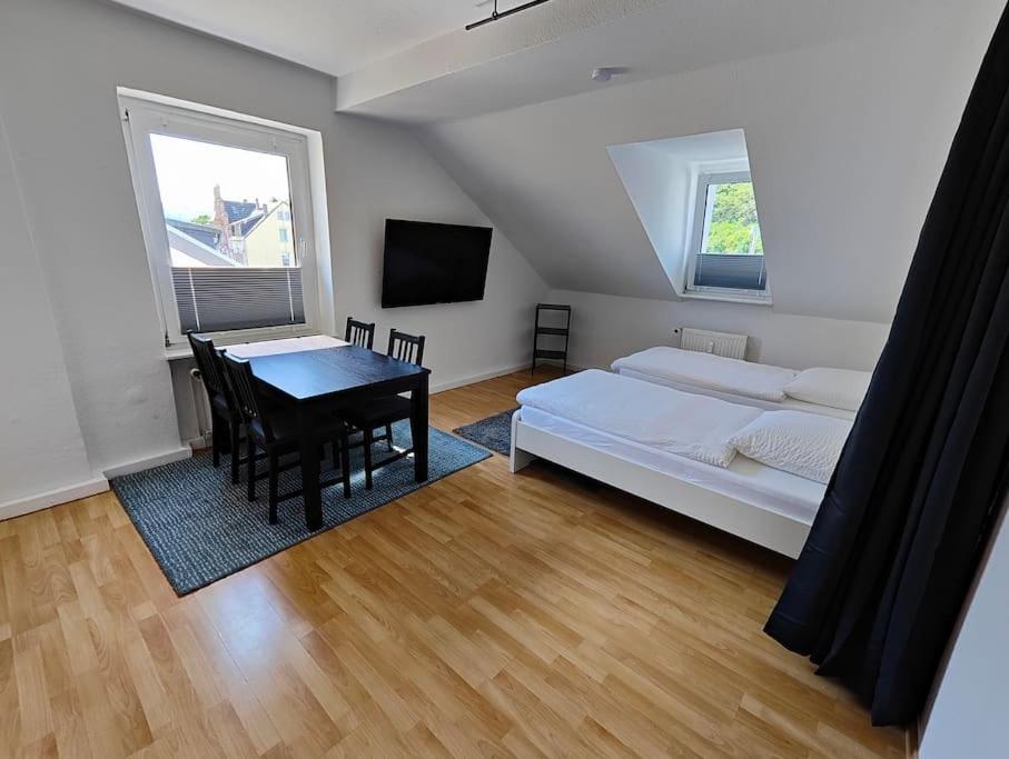 een slaapkamer met een bed en een tafel en een bed en een televisie bij SANO Apartments - DGL - Hagen Zentral - vollausgestattete Küche - Internet - Platz für bis zu 5 Personen in Hagen