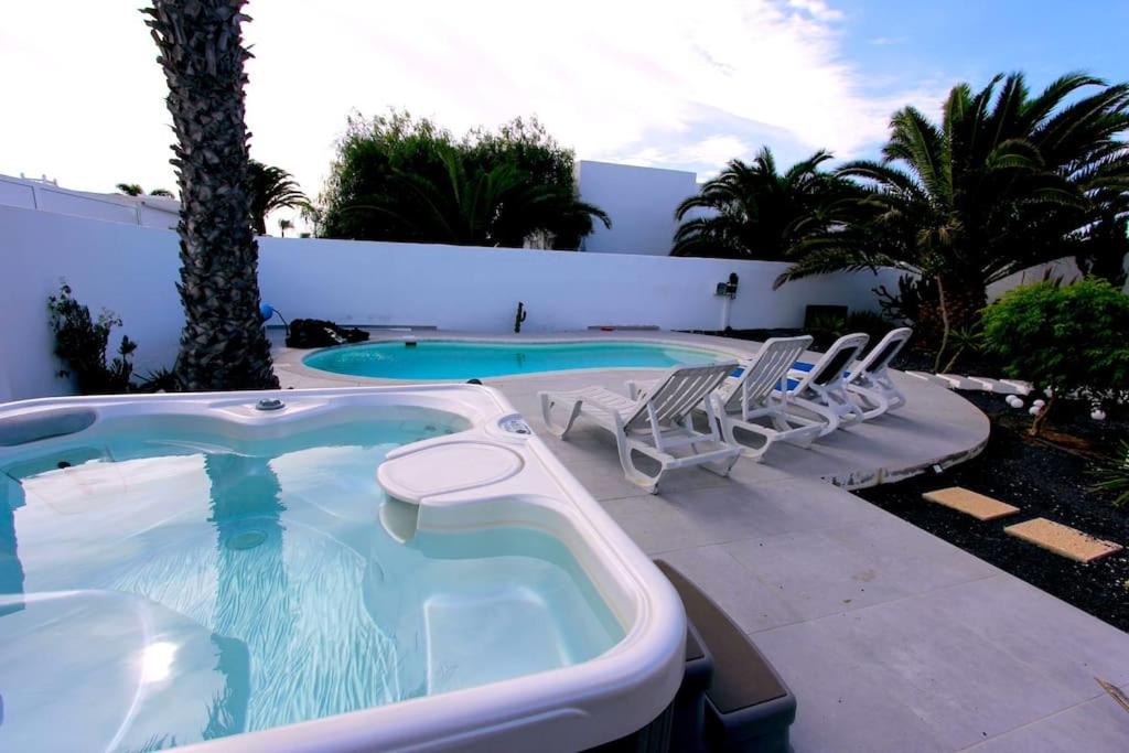 a swimming pool with chairs and a hot tub at Casa Alizée, heated pool, hot tub in Playa Blanca