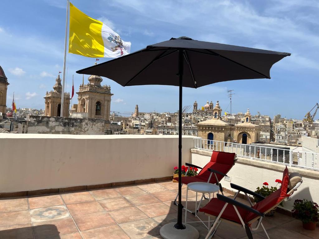 a table and two chairs and an umbrella on a roof at The Knight - Historical terraced house overlooking the central square in Birgu