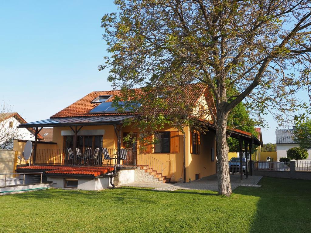 una casa amarilla con un árbol en el patio en Ferienhaus Michi, en Sankt Andrä bei Frauenkirchen