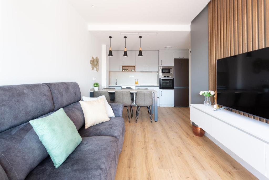 a living room with a gray couch and a kitchen at Precioso apartamento en la playa in Castelldefels