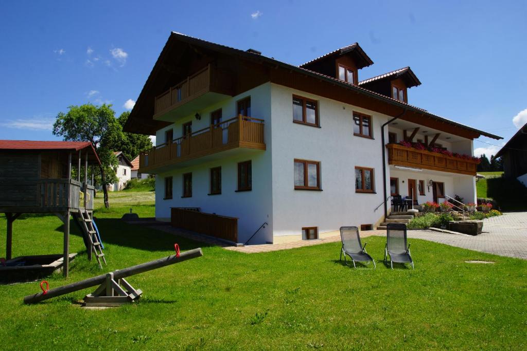 une maison avec des chaises dans l'herbe devant elle dans l'établissement Ferienwohnungen Paukner, à Sankt Englmar