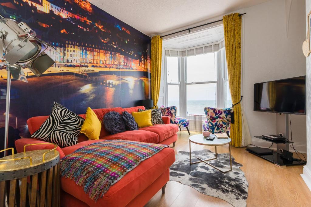 a living room with a red couch and a tv at Sea view Ar Lan y Mor LUXURY APARTMENT in Aberystwyth