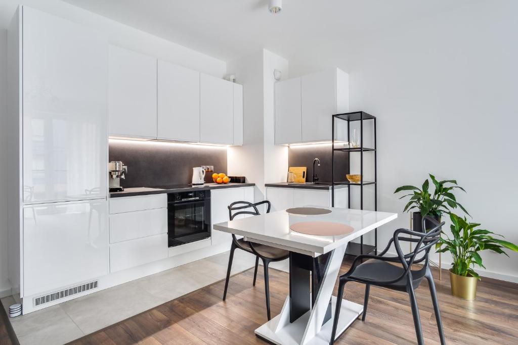 - une cuisine avec des placards blancs, une table et des chaises dans l'établissement Apartament Chwaliszewo, à Poznań