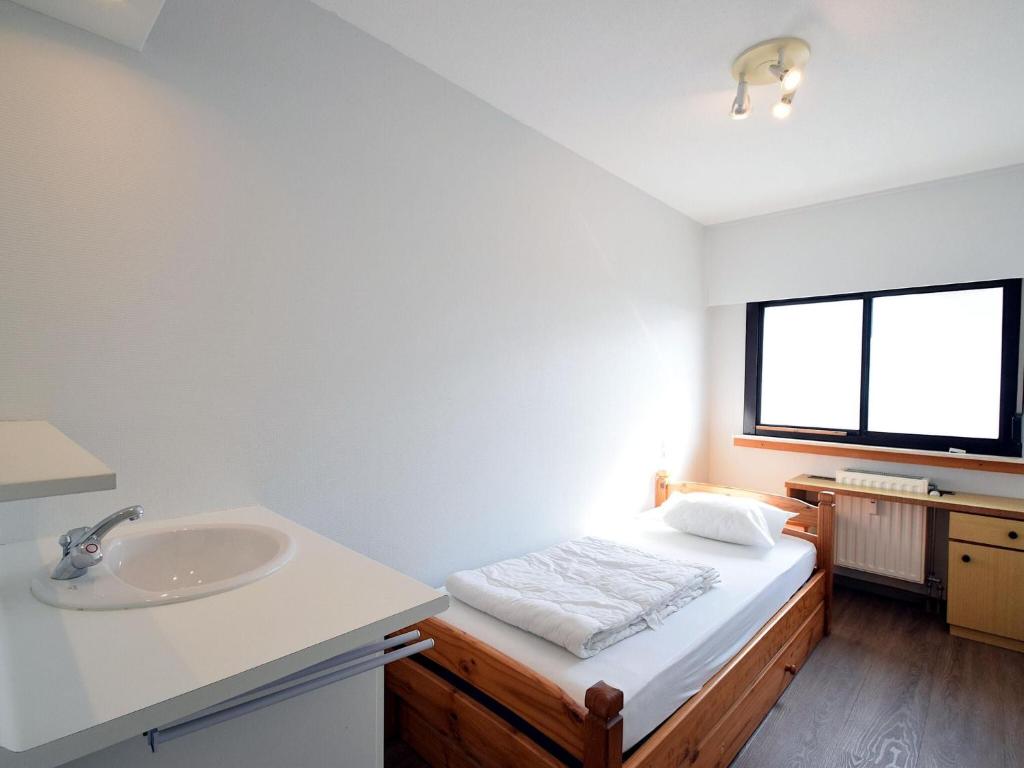 a bathroom with a bed and a sink and a window at Golf 0401 seafront apartment with balcony in De Haan