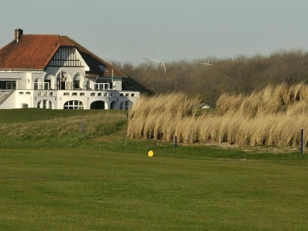 a large white house with a yellow ball in the grass at Golf 0401 seafront apartment with balcony in De Haan