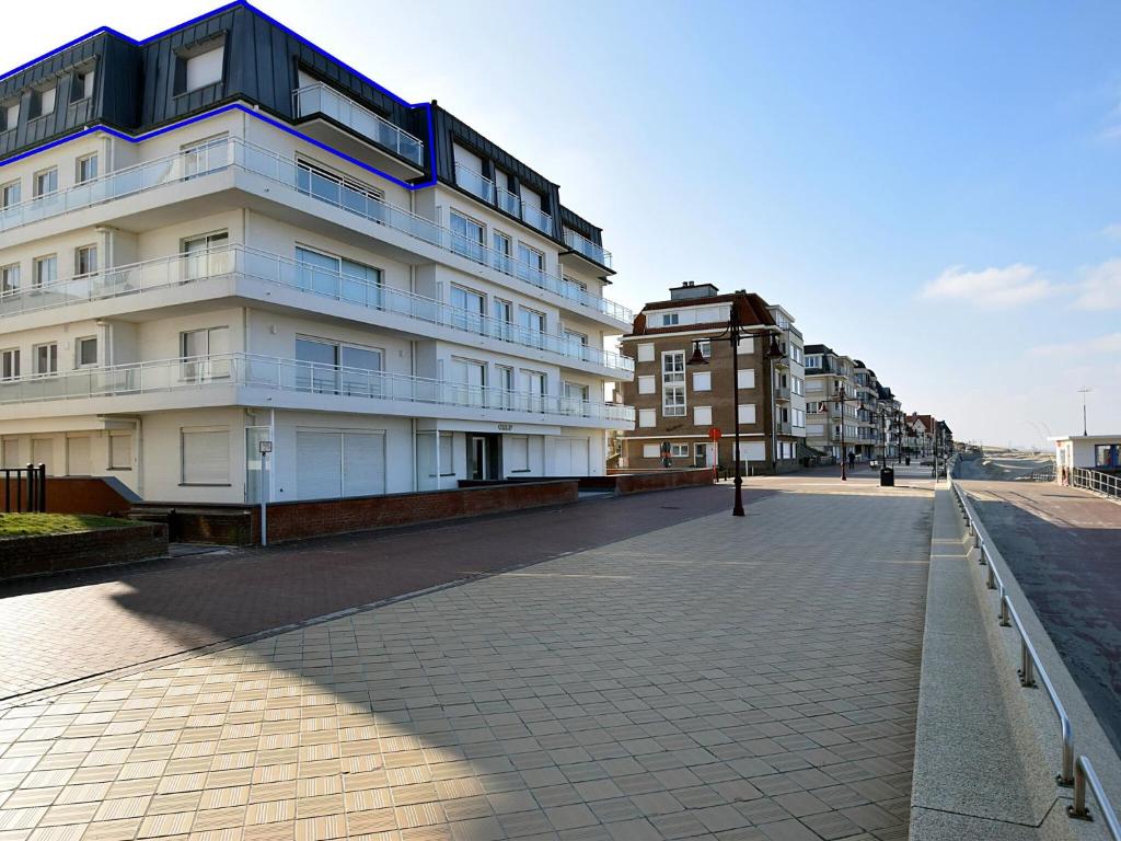 a building on a sidewalk next to a street at Golf 0401 seafront apartment with balcony in De Haan