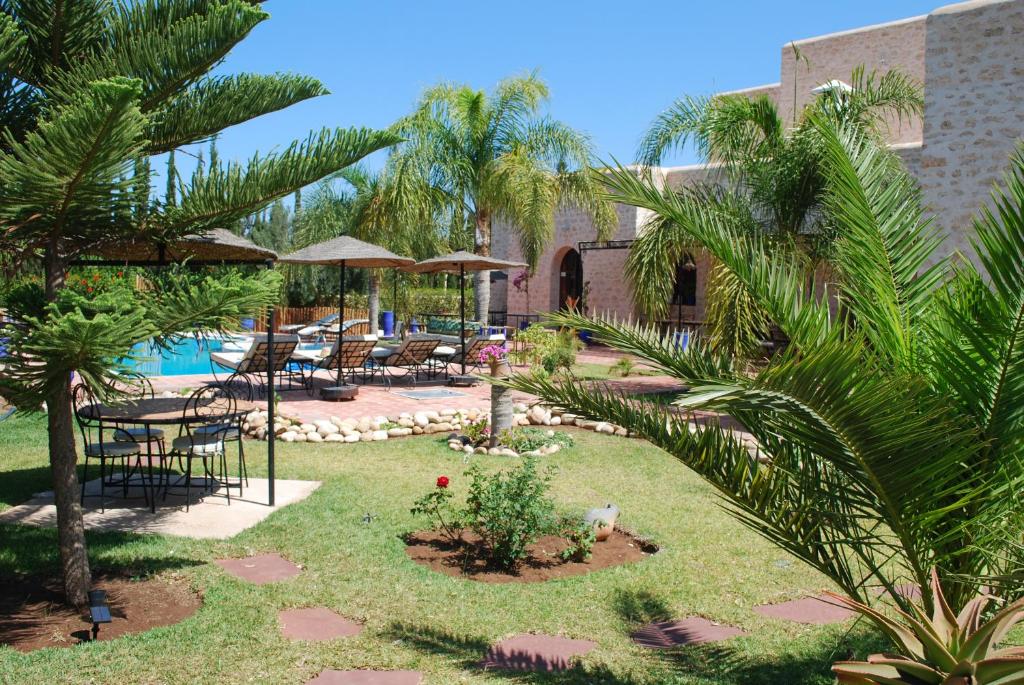 a resort with a pool and chairs and palm trees at Riad Titima Essaouira in Essaouira