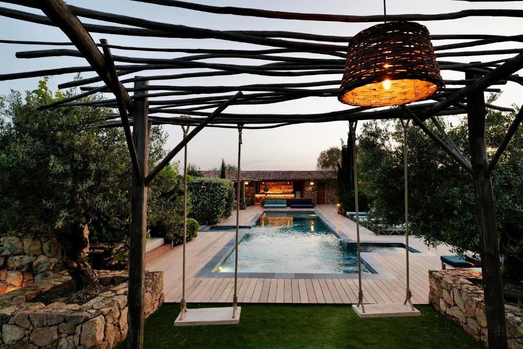 a pergola over a swimming pool in a yard at Domaine Pozzo di Mastri in Figari
