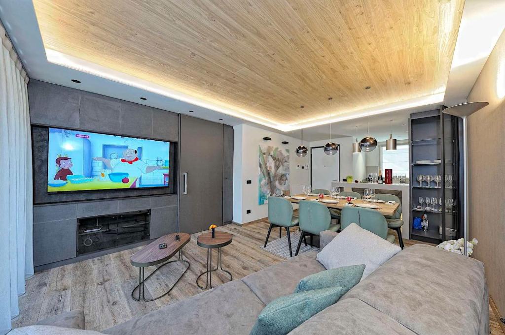 a living room with a couch and a tv and a table at Lux Domotic Apt-Chalet Dolomites in Pinzolo