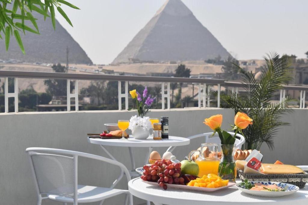 a table with food on a balcony with the pyramids at La Perle Pyramids in Cairo