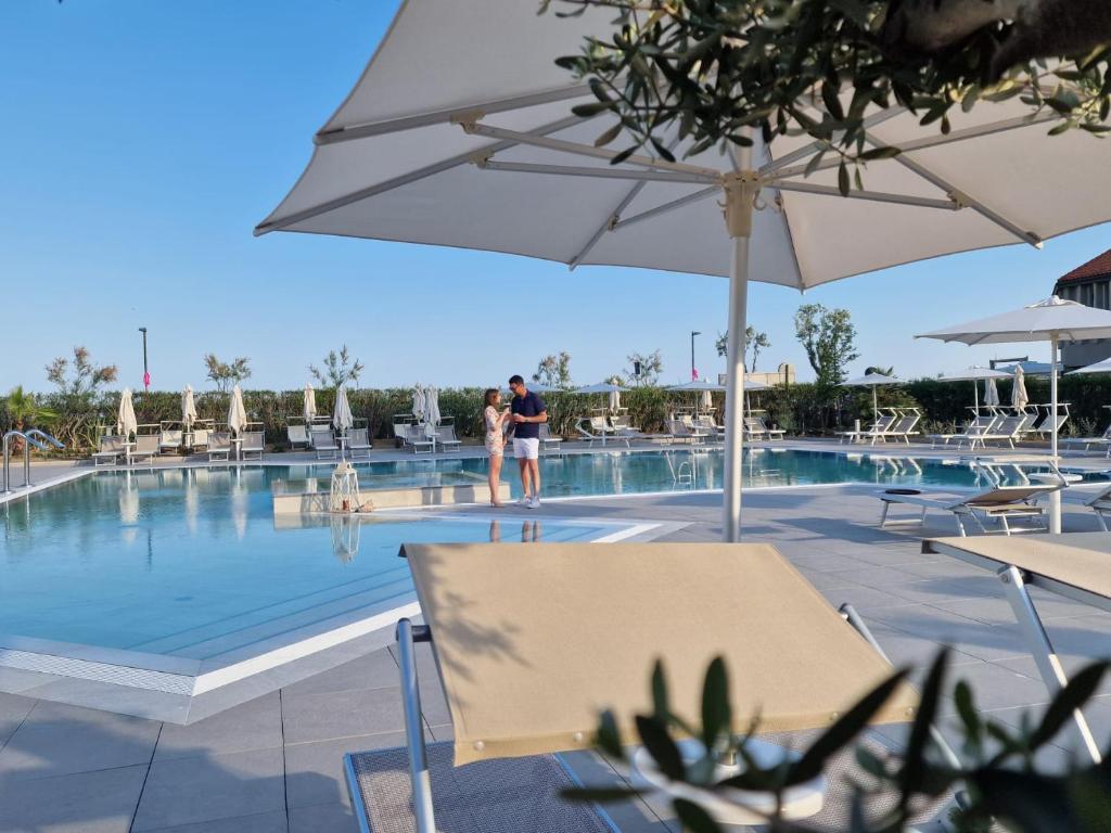 two people standing by the swimming pool at a resort at Fantinello Hotel in Caorle