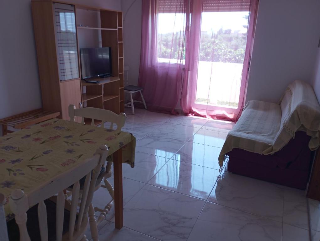 a room with a table and a bed and a tv at Apartmani Marina in Rab