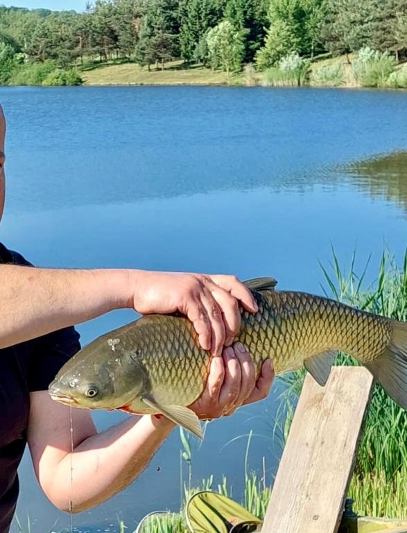 a man holding a fish in front of a lake at Family Resort in Mostiska