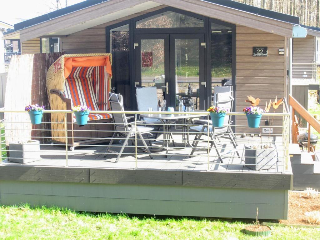 eine abgeschirmte Veranda eines Hauses mit einem Tisch und Stühlen in der Unterkunft Spatzennest Beach Chalet 22 in Scharbeutz