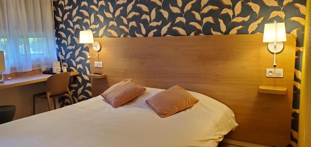 1 dormitorio con 1 cama con 2 almohadas en KYRIAD HONFLEUR - La Riviere Saint Sauveur, en Honfleur