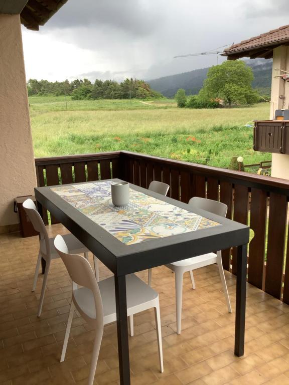 uma mesa e cadeiras numa varanda com vista para um campo em Passione Dolomiti em Romeno