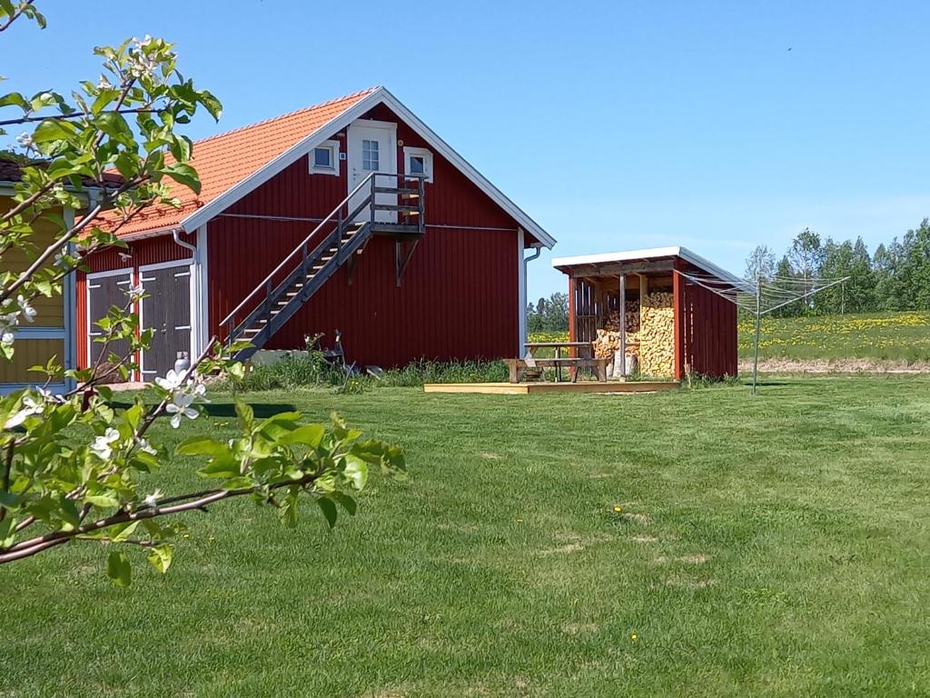 a red barn with a porch and a house at Lägenhet på landet in Torsby