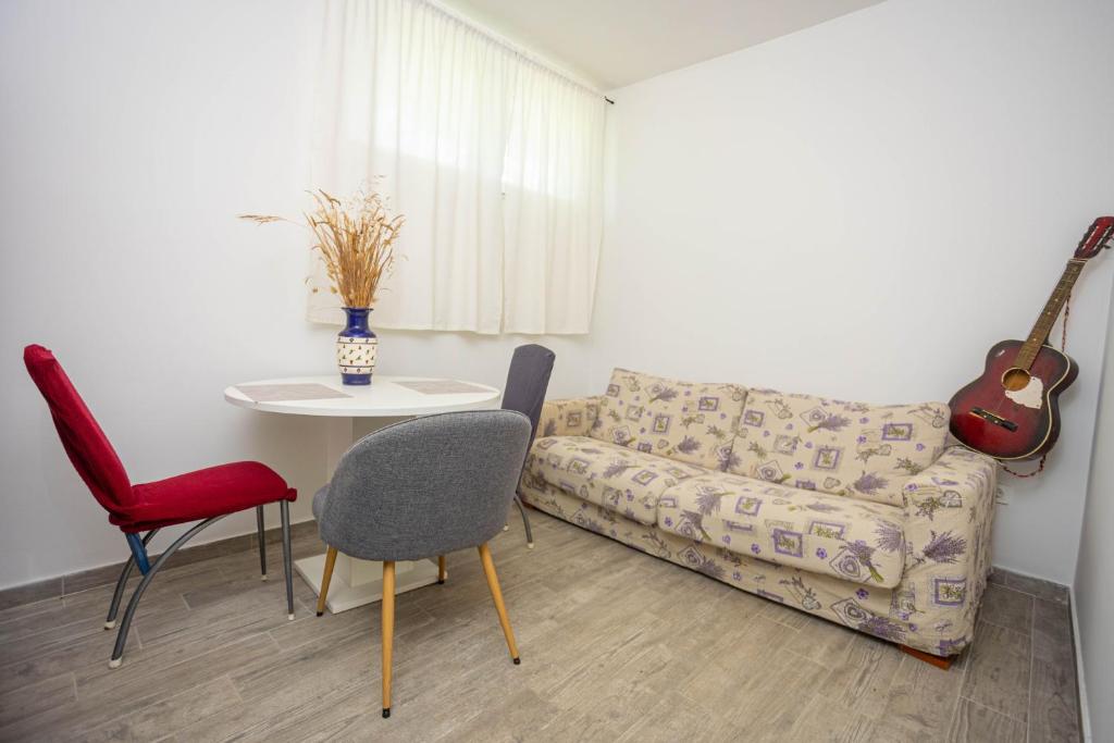 un soggiorno con divano, tavolo e chitarra di Soba sa kupaonicom a Solin (Salona)