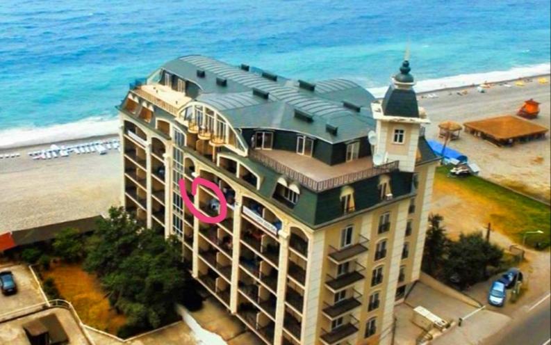 un edificio con un cartel rosa junto a la playa en Sunset kvariati, en Kvariati